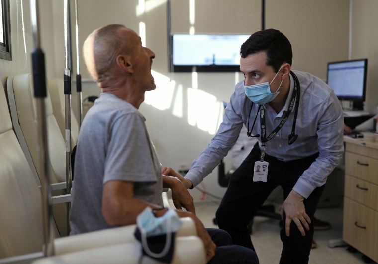 Image: Vinicius Molla, a hematologist and volunteer of the clinical trial of Oxford COVID-19 vaccine, examines a patient at a consulting room in Sao Paulo, Brazil