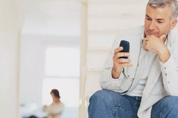 Man-checking-text-messages-with-partner-in-the-distance.jpg